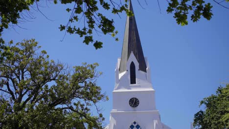 traditional cape dutch church tower appearing through oak trees in clear blue sky as moving towards it in stellenbosch