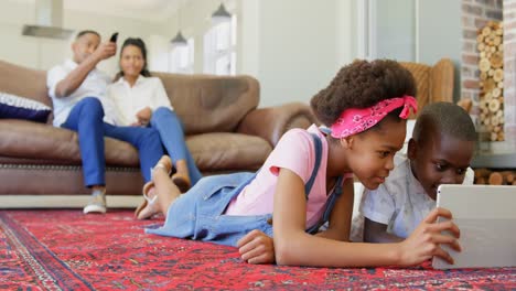 front view of black children lying on the floor and using digital tablet in a comfortable home 4k