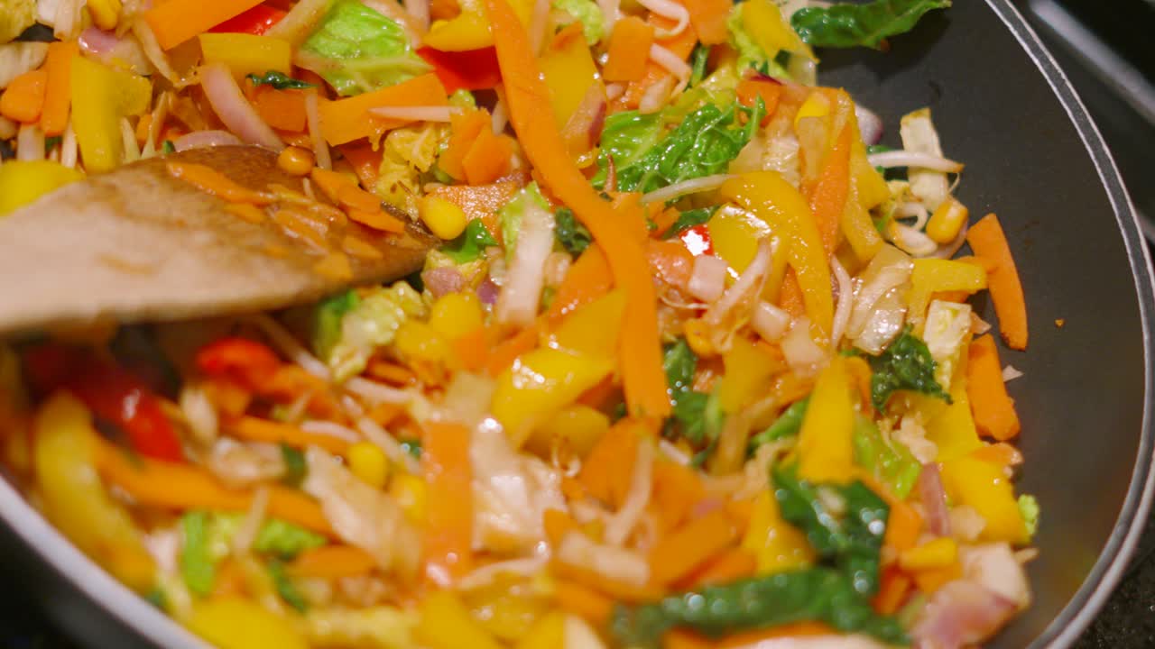 Top Rotating View of Colorful Oriental Stir Fry Vegetables in Hot Wok Pan including Carrots, Beansprouts, Peppers, Onions