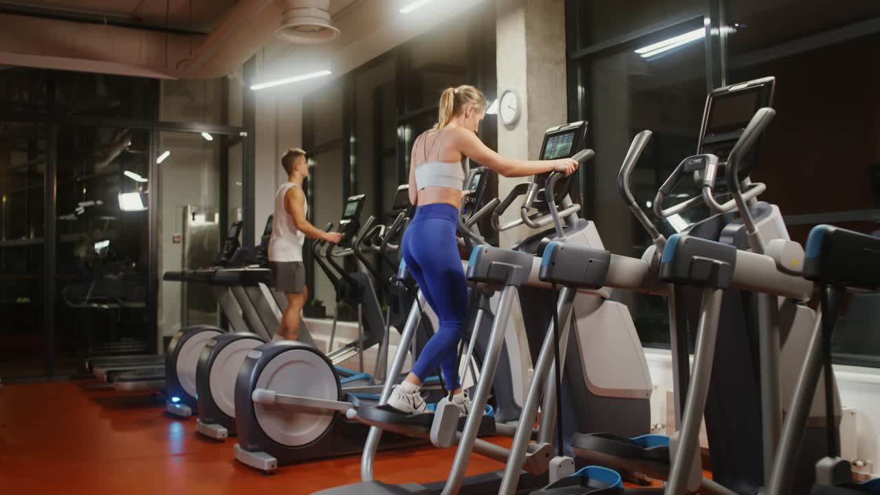 Persone che si allenano sui tapis roulant in palestra di notte