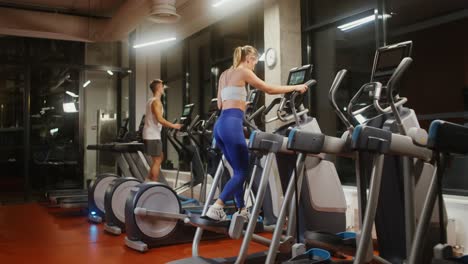 people exercising on treadmills in a gym at night