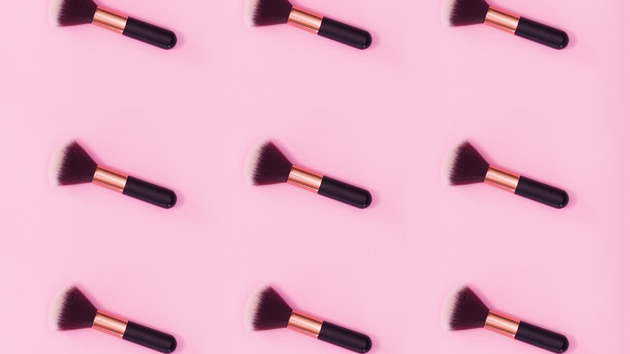 Beauty concept pattern made of make up brushes rotate on bright pink background. Stop motion