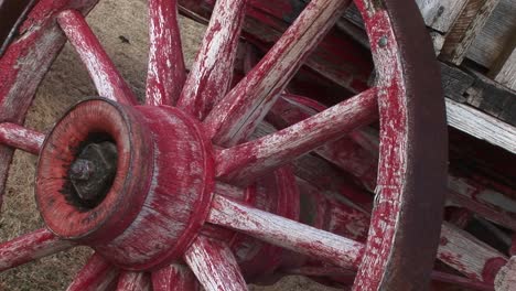 a worn covered wagon wheel shows the remains of its original red paint