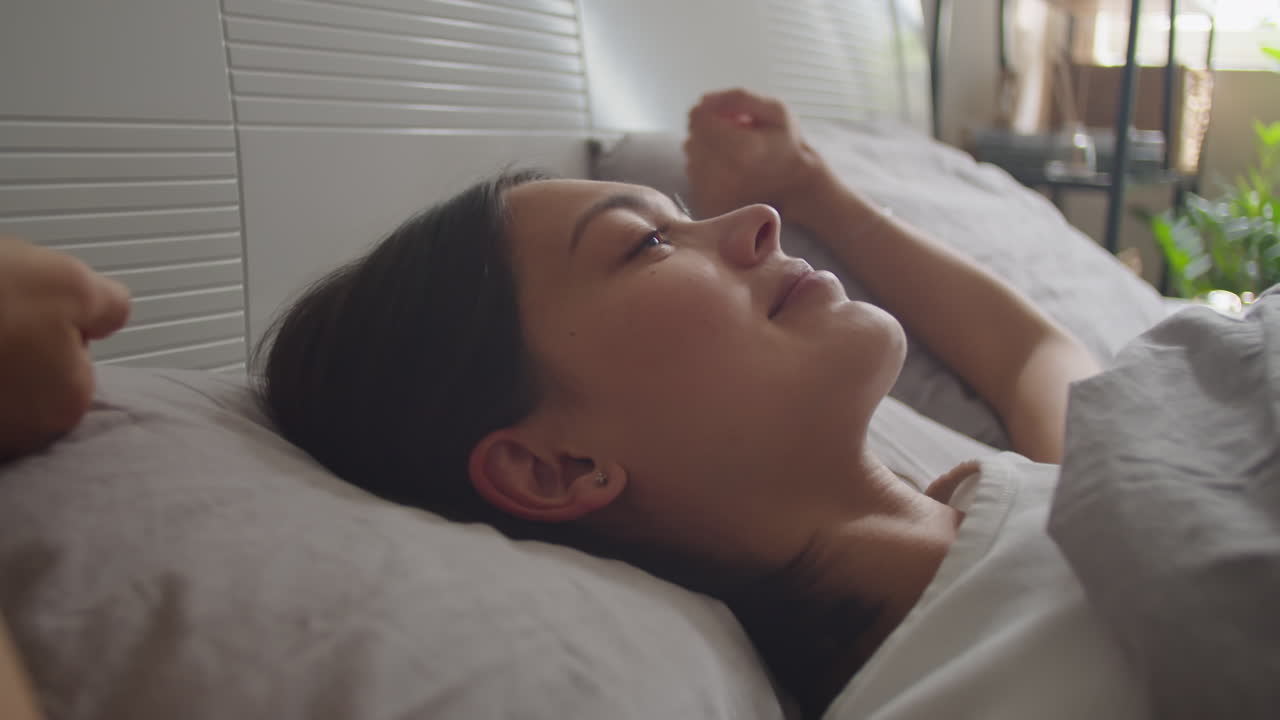 Young Woman Waking Up in Bed and Smiling
