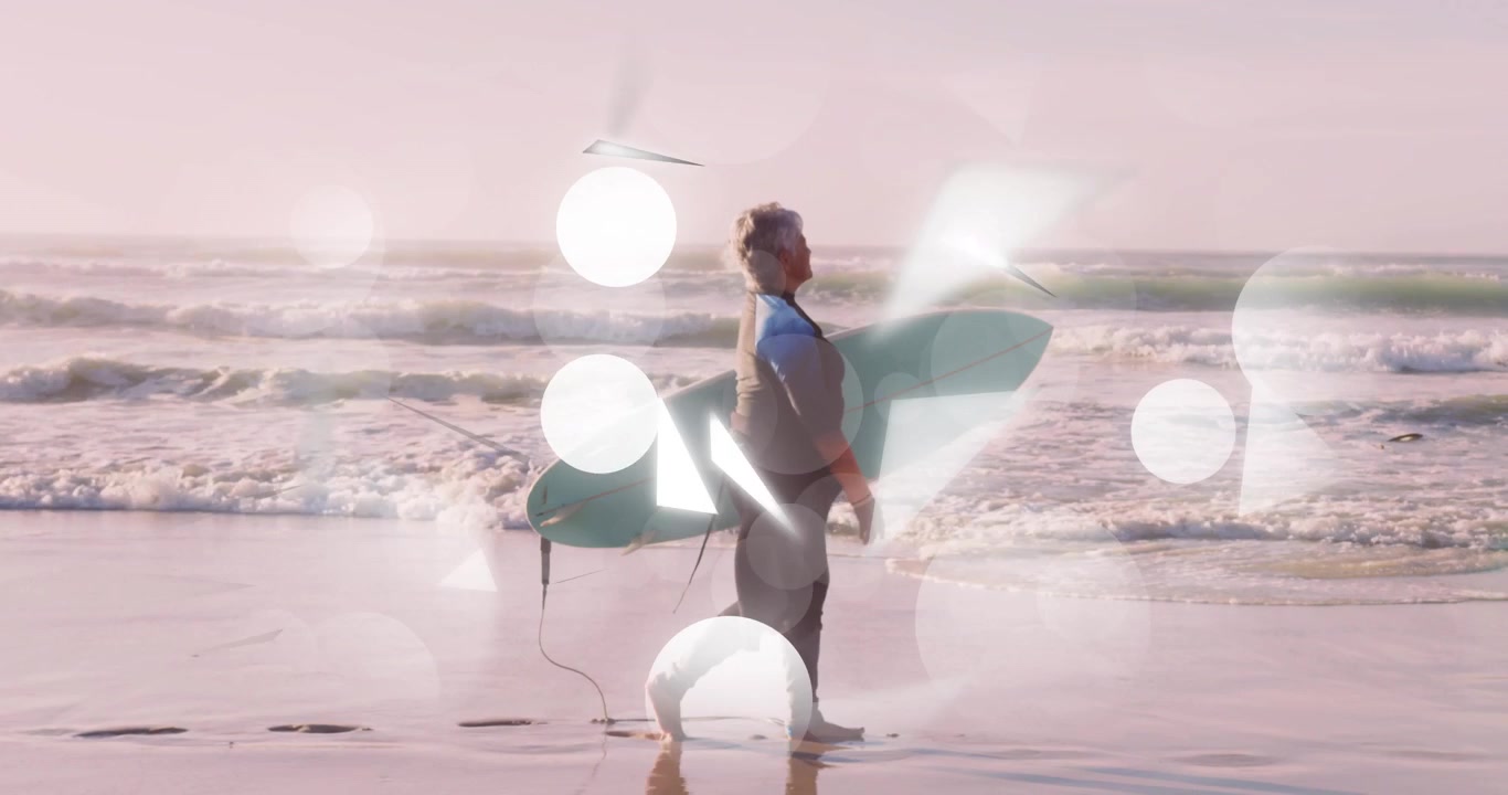 Senior surfer emerging waterline walking, carrying surfboard toward waves, light bokeh drifting