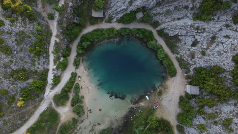 Gente-Haciendo-Un-Picnic-En-El-Manantial-Del-Río-Cetina,-También-Conocido-Como-El-Ojo-De-La-Tierra,-Un-Manantial-Kárstico-Frío-Y-Un-Agujero-Azul-Profundo,-Croacia