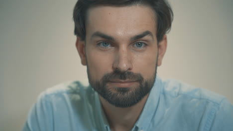 close up portrait of young handsome man with beard and blue eyes looking at camera