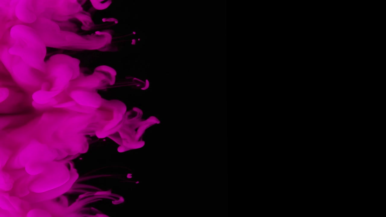 Inchiostro rosa che si diffonde nell'acqua su sfondo nero