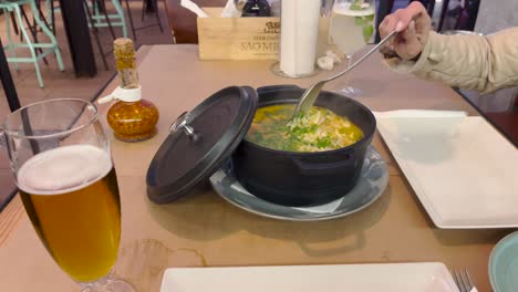 pot of soupe served on a table by a waiter and stirred by a woman. static