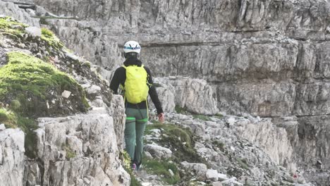 female mountaineer with climbing gear in the dolomites walking on a path