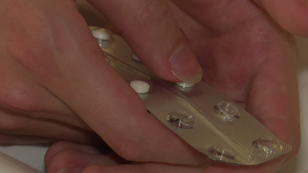 Person handling blister pack of pills