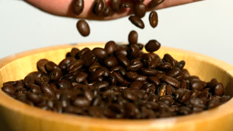 granos de café cayendo en un cuenco de madera de la mano
