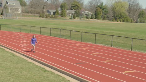 teen girl runner at the track lunges and twists in her pre run workout