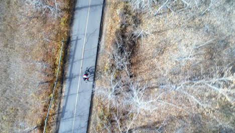 Vista-Aérea-De-Un-Ciclista-En-Bicicleta-Por-Un-Camino-Rural-En-El-Bosque-Vista-Aérea-De-Un-Ciclista-En-Bicicleta-A-Través-De-Un-Conteo