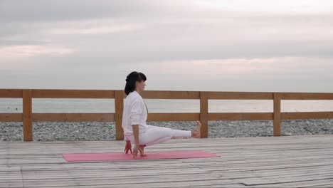 woman practicing yoga on a beach