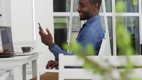 African-american-businessman-using-laptop-and-smartphone-in-cafe