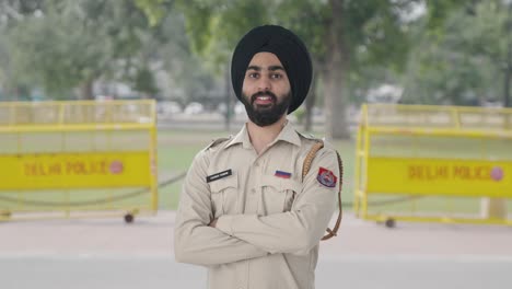 portrait of happy sikh indian police man standing crossed hands
