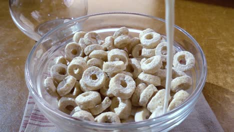 copos de avena crujientes en un tazón para un delicioso desayuno matutino con leche. cámara lenta con toma de seguimiento de rotación.