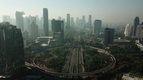 jakarta, indonesia. september 14, 2017: stunning aerial scenery of semanggi highway traffic and office buildings in the misty morning from a drone flying forward
