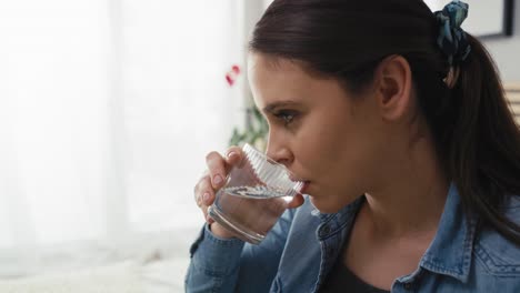 mujer caucásica embarazada a punto de tomar una píldora y beber agua.