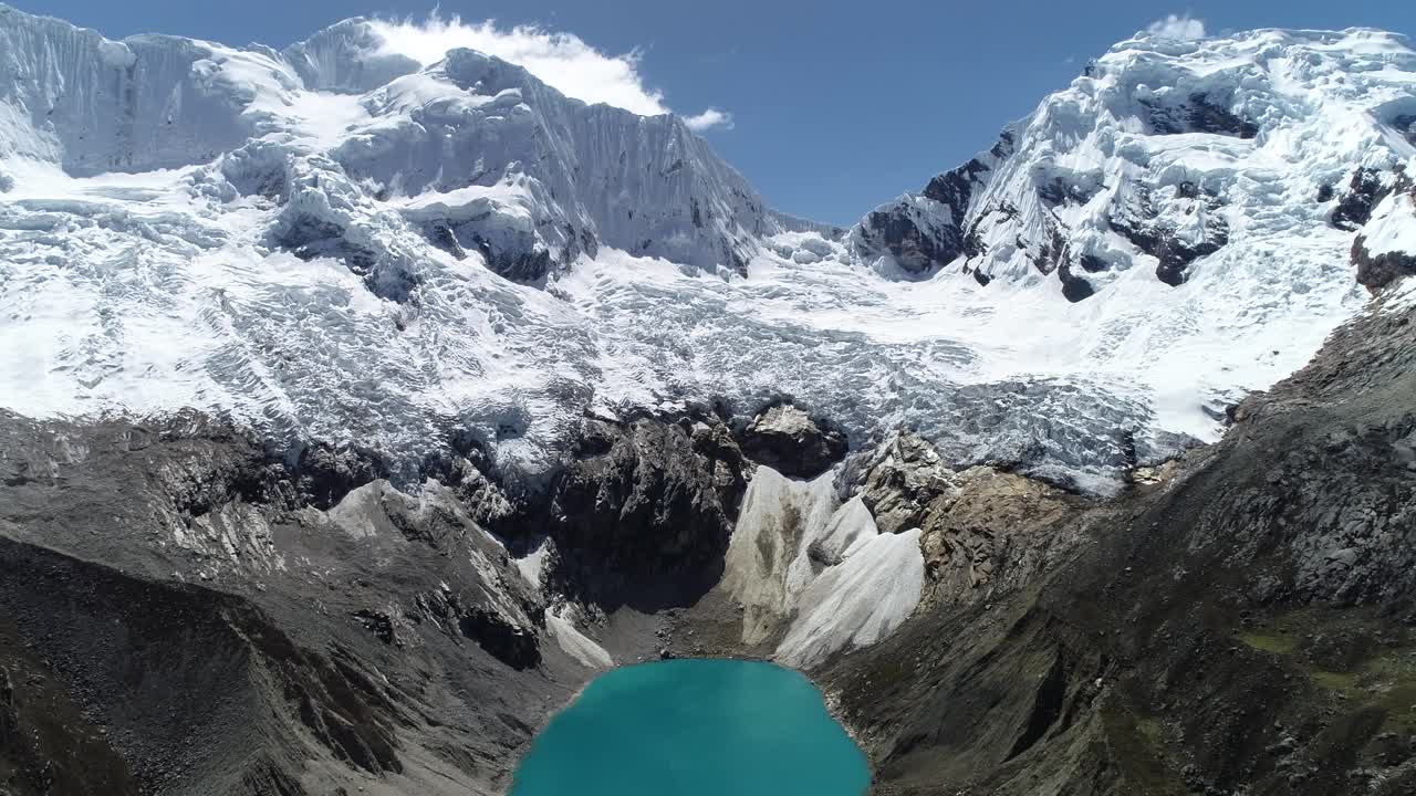 Stunning aerial shot of a glacial lagoon with turquoise waters beneath towering snow-capped peaks. Ideal for travel blogs, documentaries, and environmental projects
