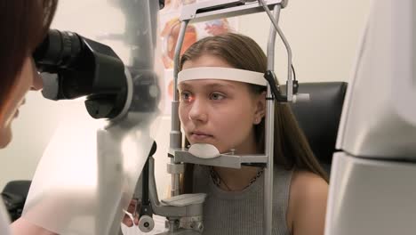 oftalmólogo chequea la vista de un adolescente con equipos modernos. médico chequeando los ojos con un dispositivo de biomicroscopio. toma de dolly de una doctora examinando la estructura del ojo con la ayuda de equipos médicos