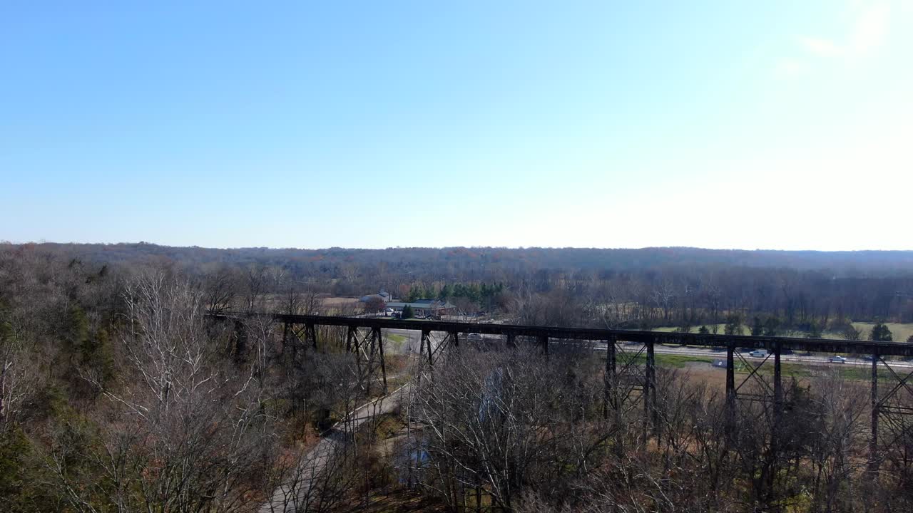 disparo aéreo empujando sobre un bosque hacia el papa lick trestle en louisville kentucky en una tarde soleada