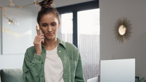 mujer caucásica sentada en el escritorio y hablando por teléfono