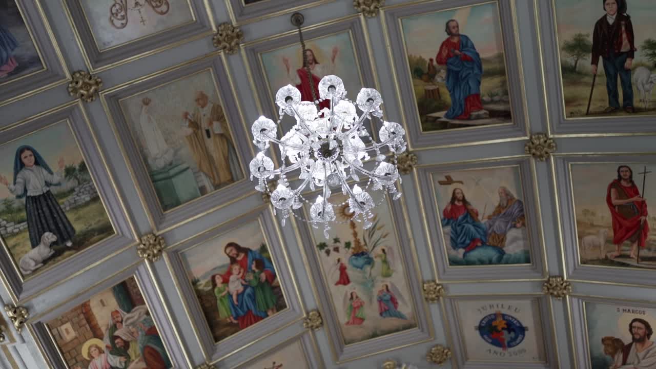 Ampia vista di un lampadario di cristallo e dipinti religiosi sul soffitto della chiesa.