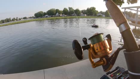 uhd, slow motion shot of a fishing pole with a person relaxing in a lake on an inter tube in the background during the summer.