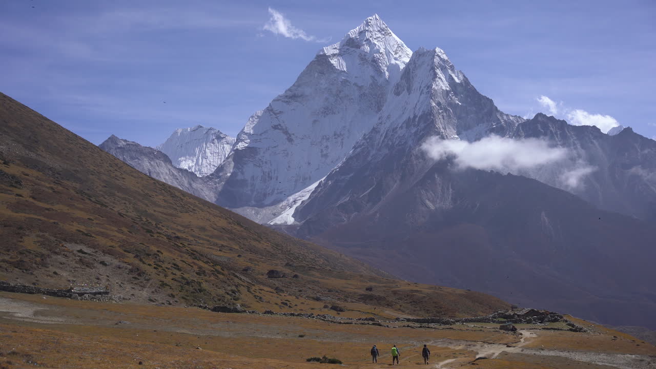 Tourists walking the Dingboche to Thukla Pass route on the Everest Base Camp trek, with Ama Dablam in the background and snow-capped mountain peaks shining in the distance