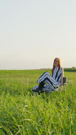 woman in striped dress jumping and sitting in a field