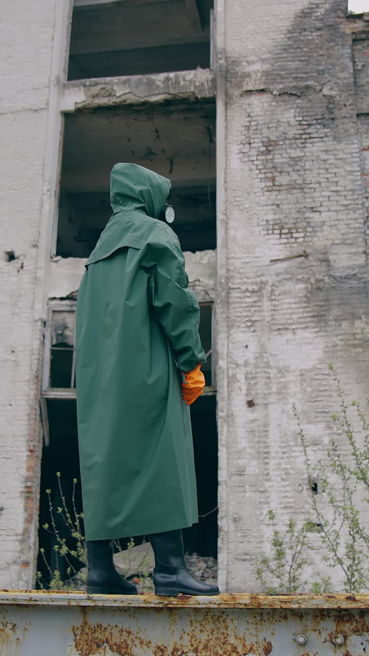 Man in special radioactive uniform walking down. Man wearing green chemical suit and gas mask. Vertical video
