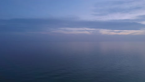 Calma-Las-Olas-Del-Océano-Después-De-La-Puesta-Del-Sol-Con-Un-Cielo-Nublado