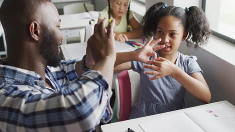 video of happy african american teacher learning african american girl how to count in classroom