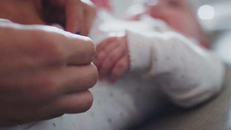 primer plano de las manos de la madre haciendo la camiseta de su bebé, bebé sonriendo, primer plano, enfoque del estante