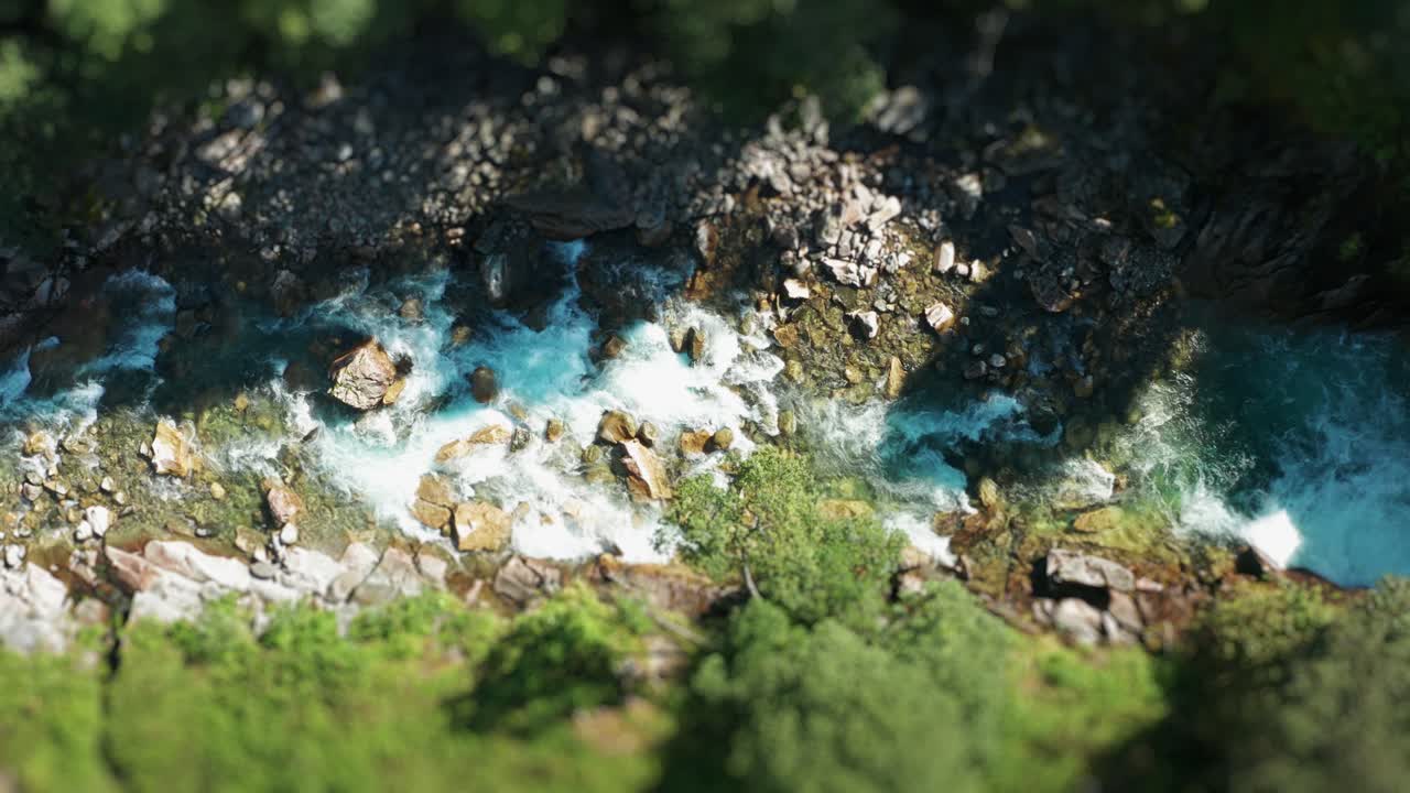 A shallow mountain river rushes through the rocky canyon