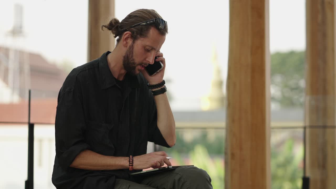 Man on a phone call using a tablet with a stylus