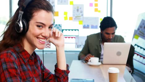 Female-graphic-designer-working-while-listening-music-at-desk