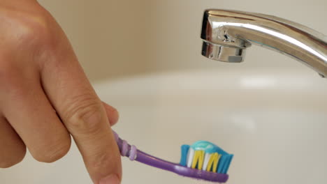 man applies toothpaste to a tooth brush