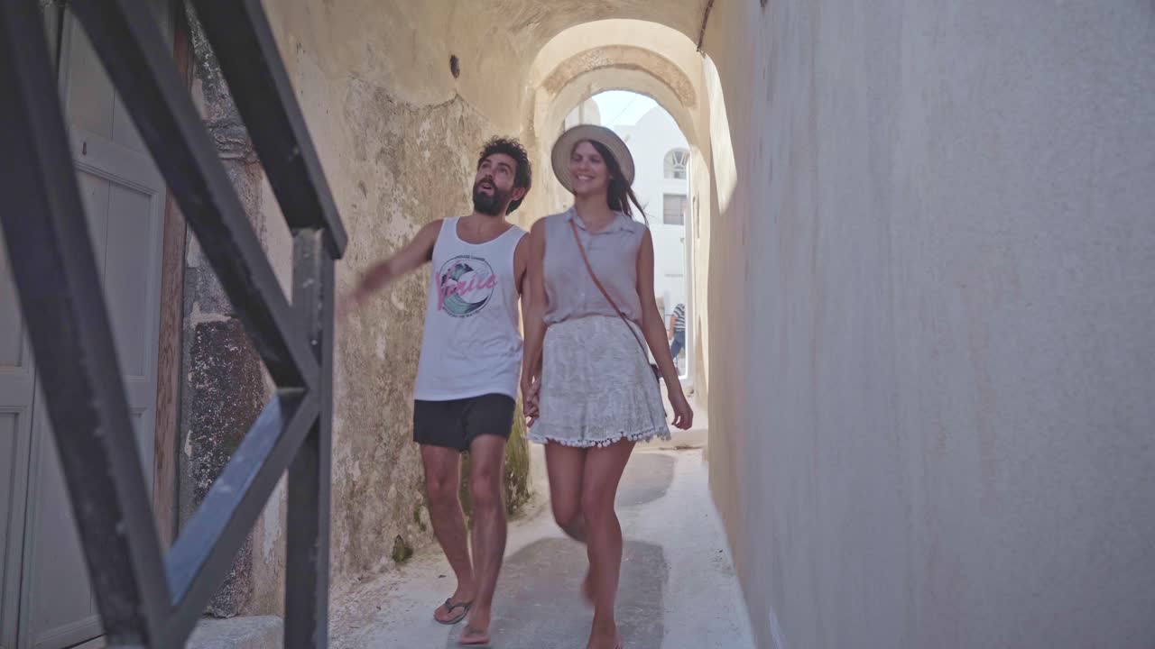 young couple holding hands have a romantic walk through the back alleyways of Mykonos, Greece