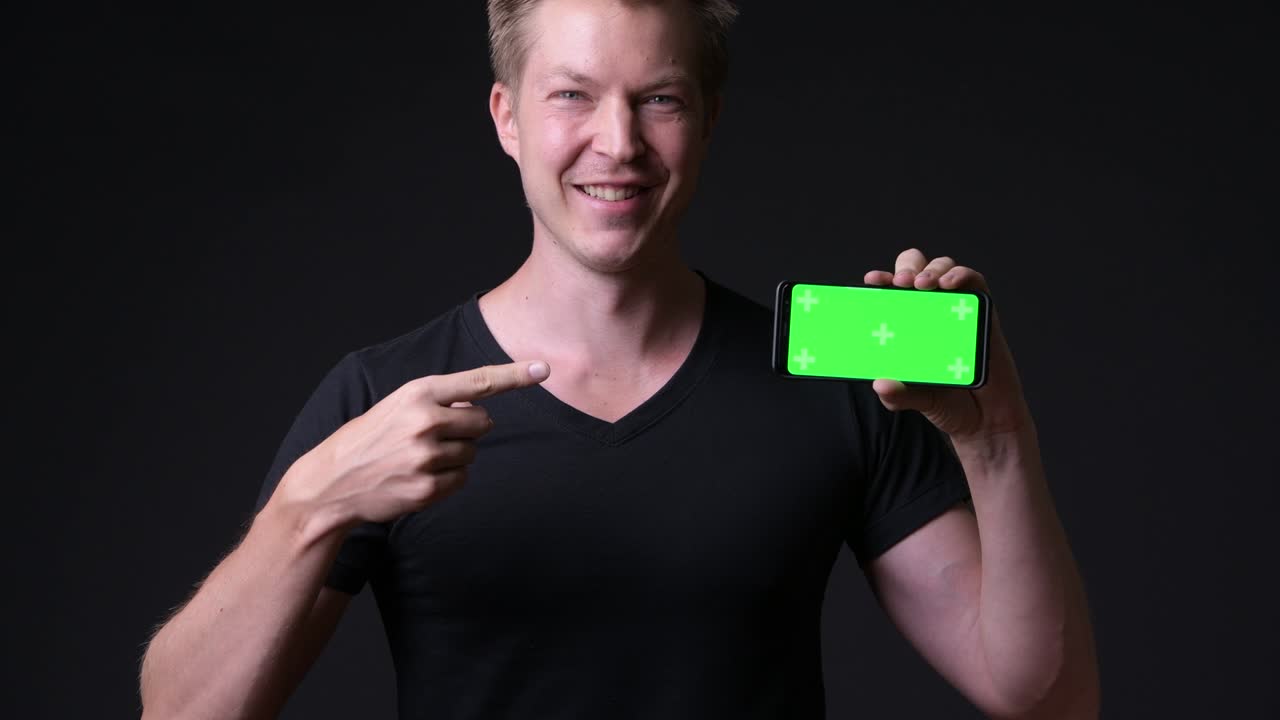 hombre feliz sosteniendo un teléfono móvil con pantalla verde de clave cromática