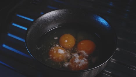 Adding-flour-to-a-cast-iron-skillet-containing-raw-eggs,-then-a-man's-hands-use-a-fork-to-whisk-the-eggs,-mixing-them-briskly-and-evenly