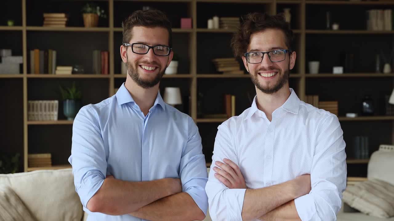 Fratelli gemelli con gli occhiali posano insieme in piedi nel soggiorno