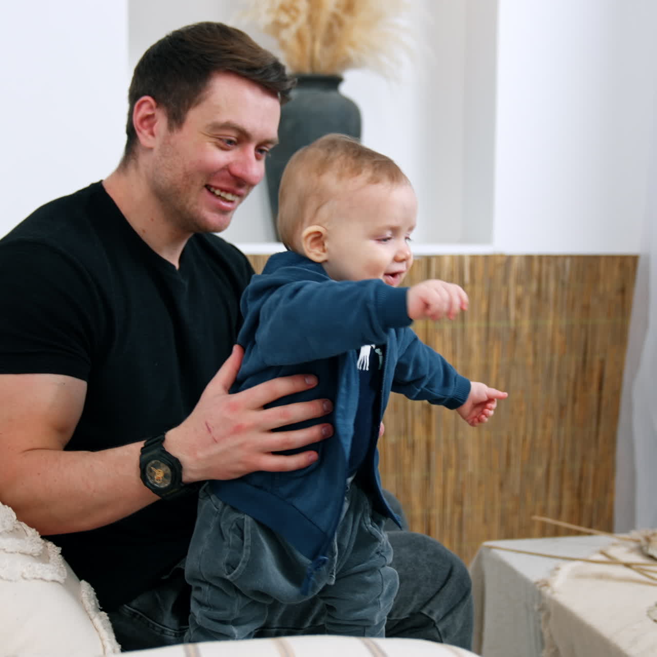 Uomo caucasico sorridente con un bambino in braccio. Il piccolo neonato impara a stare in piedi sostenuto dal padre.