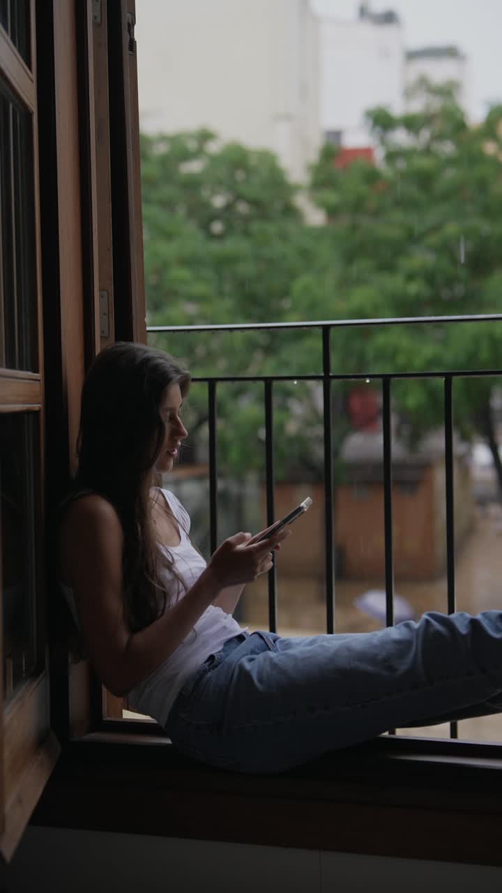 mujer tomando una selfie en un balcón de día lluvioso