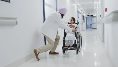 Glücklicher-Biracial-Arzt,-Der-In-Zeitlupe-Mit-Einer-Kranken-Patientin-Im-Rollstuhl-Geht-Und-Spricht