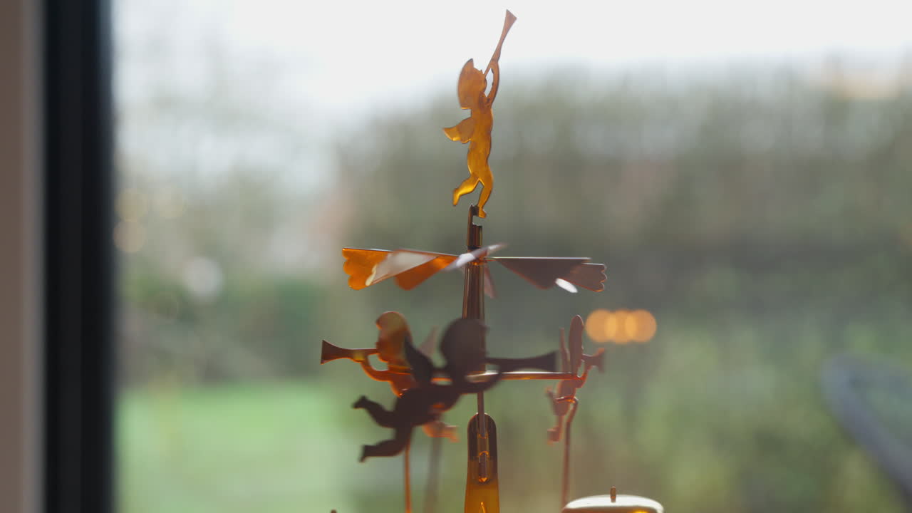 Silhouette of a whimsical angel figure on a golden carousel, against a bright window backdrop