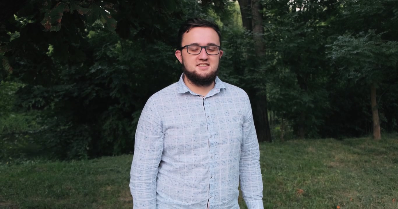 Uomo in camicia si mette gli occhiali e sorride.