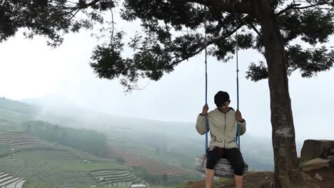 a portrait of a man swinging on a hilltop